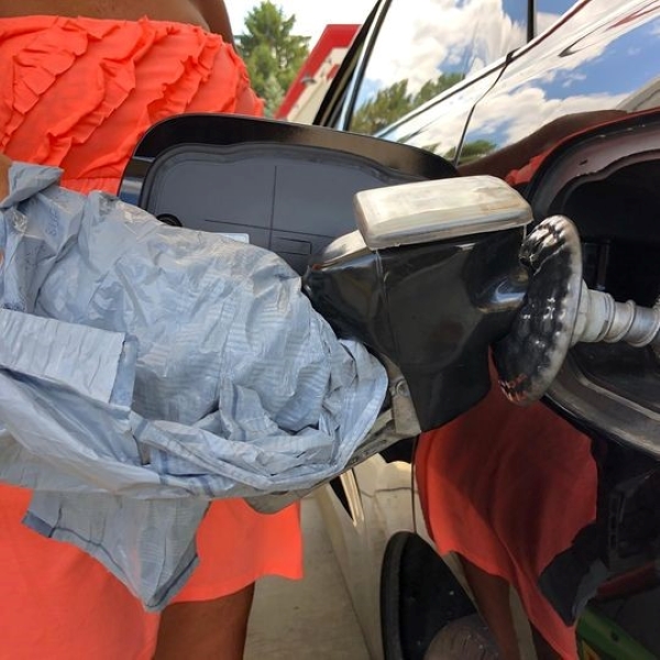 pumping gas in car hand covered in plastic