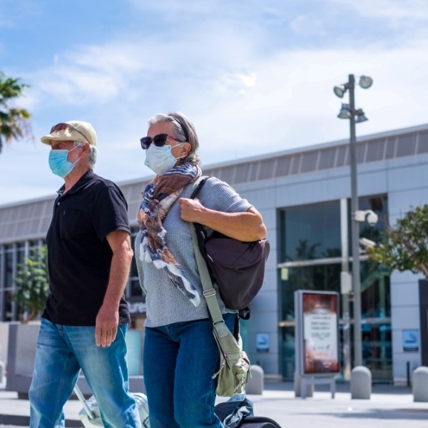 senior couple leaving airport wearing masks