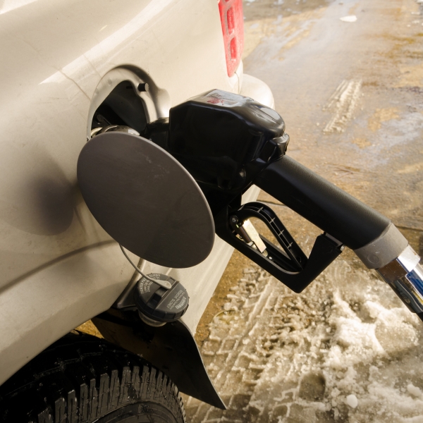 A gas pump nozzle is placed in a vehicle's gas tank opening.