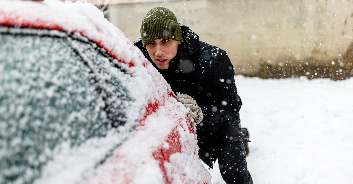 Man pushing car stuck in snow