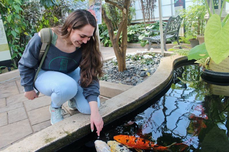 Valerie greets the koi in the pond at the botanical gardens after feeding the fish.