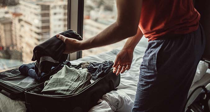 packing clothing into a piece of luggage on the bed