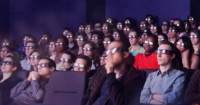 Audience members sit in an omnitheater, wearing 3D glasses